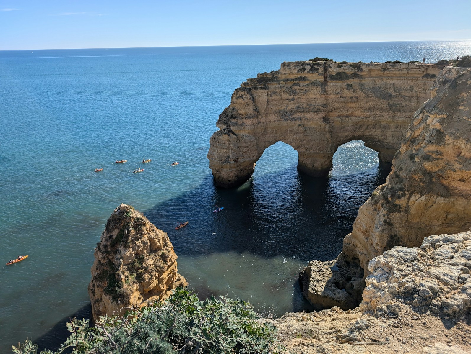 Arching cliffs meet the ocean on a sunny day.